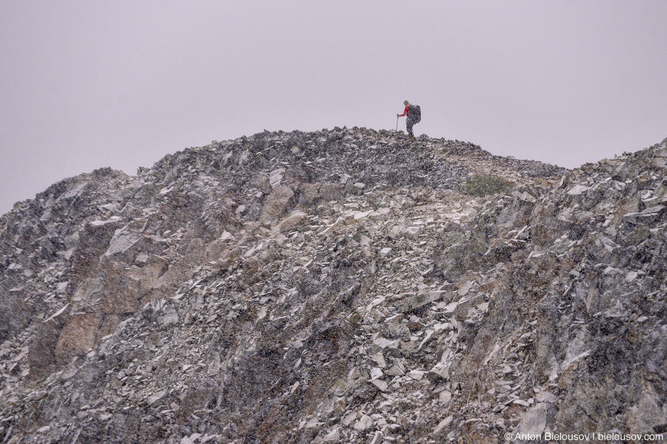 Hiker in snowfall at Frosty Mountain peak, BC